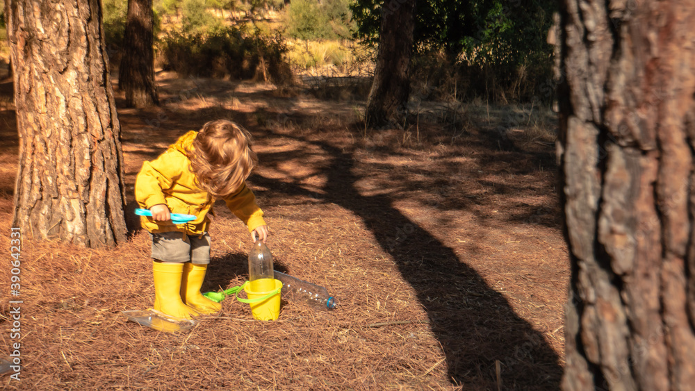 Young child is picking up plastic waste in the forest as a volunteer. Toddler and young children early environmental education concept. Young child is picking up plastic waste in the forest as a volunteer. Toddler and young children early environmental education concept.