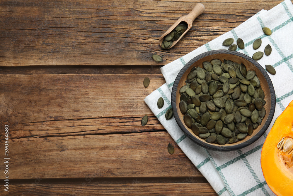 Peeled seeds and fresh pumpkin on wooden table, flat lay. Space for text Peeled seeds and fresh pumpkin on wooden table, flat lay. Space for text