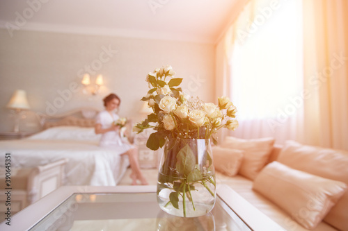 A pretty young girl. Bride's boudoir morning. Sitting on the bed with a bouquet of flowers
