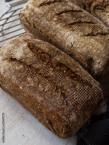 Home made, wholesome rye and whole wheat sourdough bread in natural light on cooling rack.
