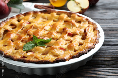 Traditional apple pie with mint on black wooden table, closeup