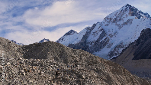 People hiking through the rock-covered majestic Khumbu glacier on the way to village Gorakshep on Everest Base Camp Trek with snow-capped Nuptse in the Himalayas, Sagarmatha National Park, Nepal. © Timon