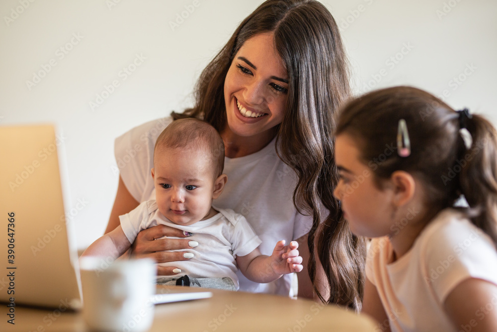 Mother playing with her daughter and baby boy in living room.They using laptop to watch cartoons. Mother playing with her daughter and baby boy in living room.They using laptop to watch cartoons.