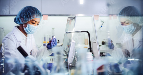 Asian female doctor working on biohazardous samples in laboratory. Using microscope