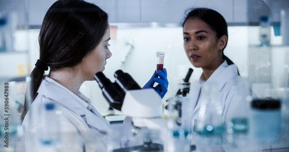Multi ethnic science team working with microscope and computer. Female doctors in futuristic laboratory Multi ethnic science team working with microscope and computer. Female doctors in futuristic laboratory