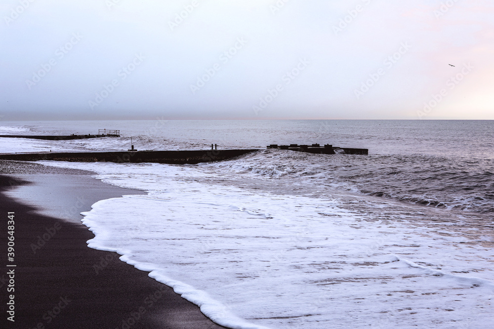 Fototapeta premium Seaside with black sand, white foam and skyline