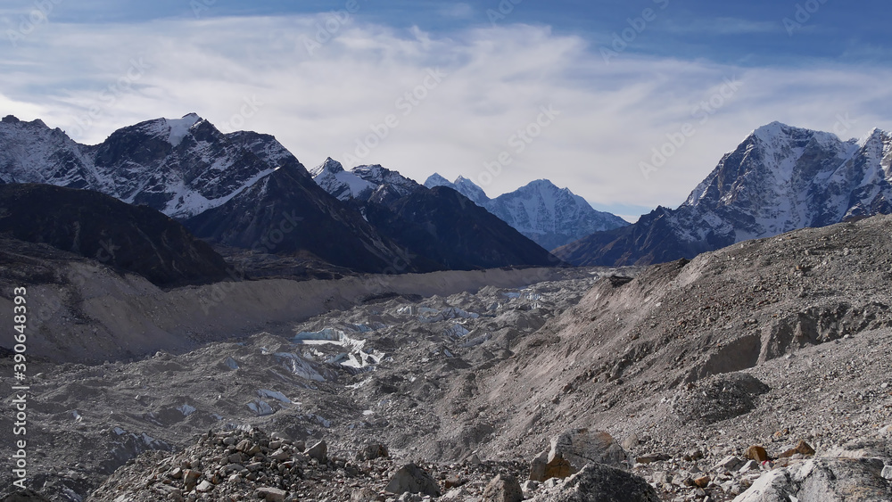 Beautiful panoramic view of rock-covered Khumbu glacier surrounded by majestic snow-capped mountains in the Himalayas on Mount Everest Base Camp Trek in Sagarmatha National Park, Nepal. 