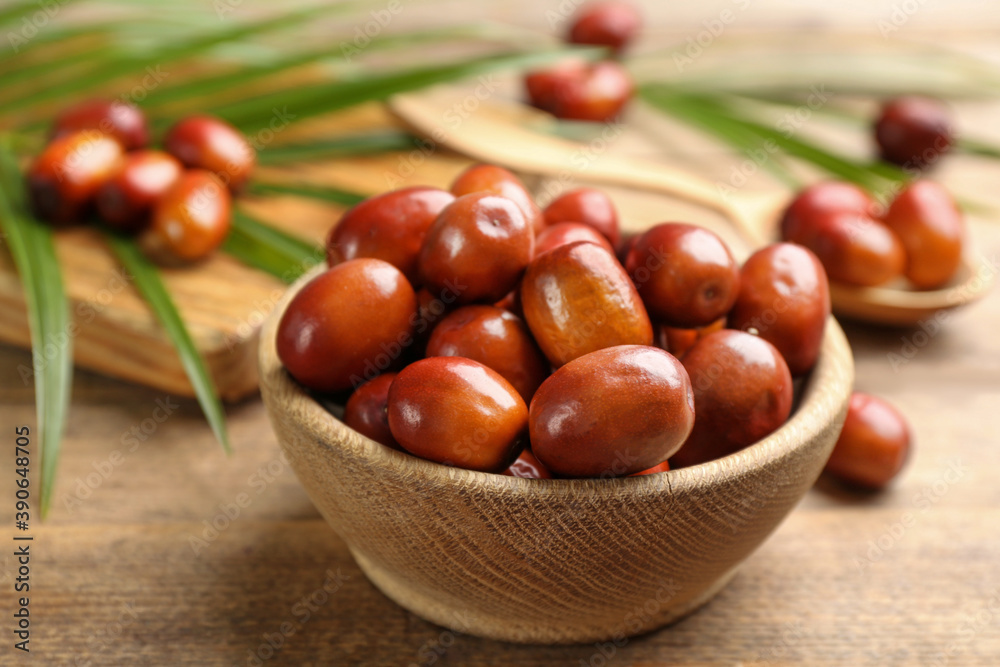 Palm oil fruits in bowl on wooden table, closeup Palm oil fruits in bowl on wooden table, closeup