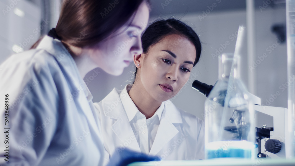 Modern laboratory. Female scientists working with microscope. Testing biohazardous samples Modern laboratory. Female scientists working with microscope. Testing biohazardous samples