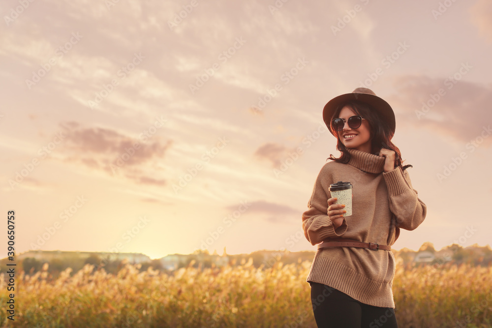 Beautiful young woman with cup of coffee wearing stylish autumn sweater outdoors Beautiful young woman with cup of coffee wearing stylish autumn sweater outdoors