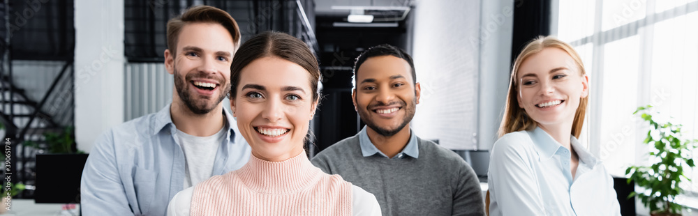 Multiethnic businesspeople smiling at camera in office, banner