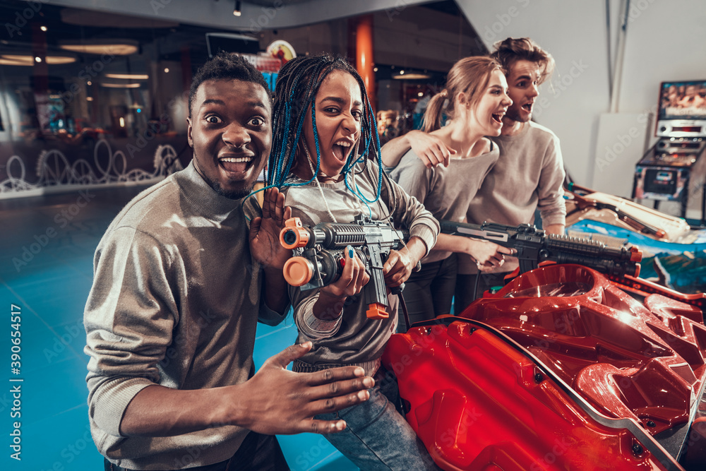 Group of young friends posing with guns in arcade.