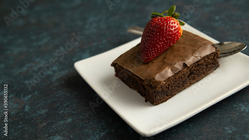 brownie with strawberry on plate on textured background photo