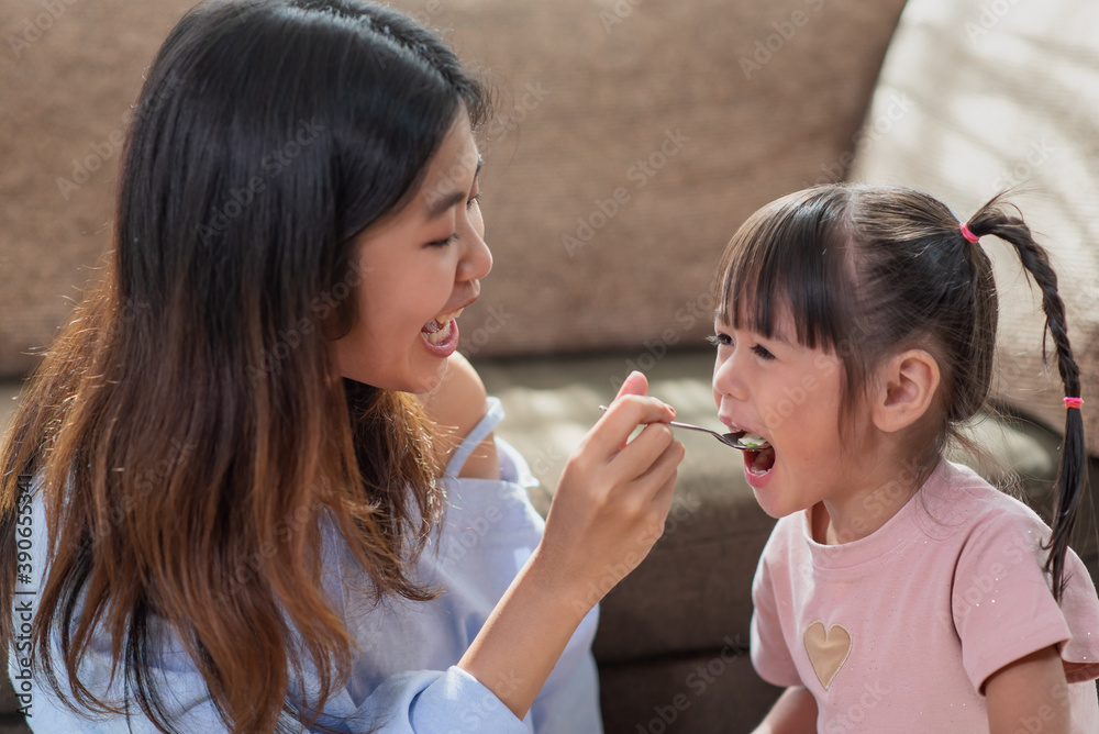 Happy Asian child enjoy eating tasty cake with her older sister Happy Asian child enjoy eating tasty cake with her older sister