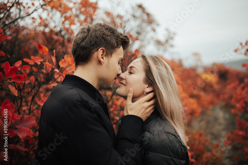 Close up portrait of young loving couple over autumn red leaves background. Romantic walk.