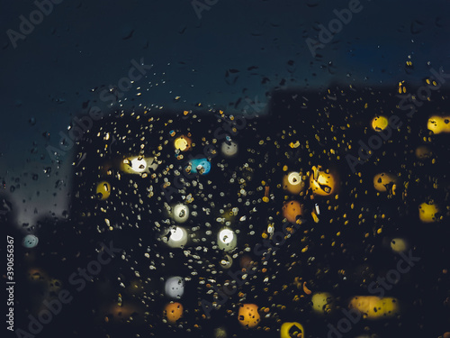 Raindrops on the window, night raindrops with light reflection from the house, blurred backgroundRaindrops on the window, night raindrops with light reflection from the house, blurred background photo