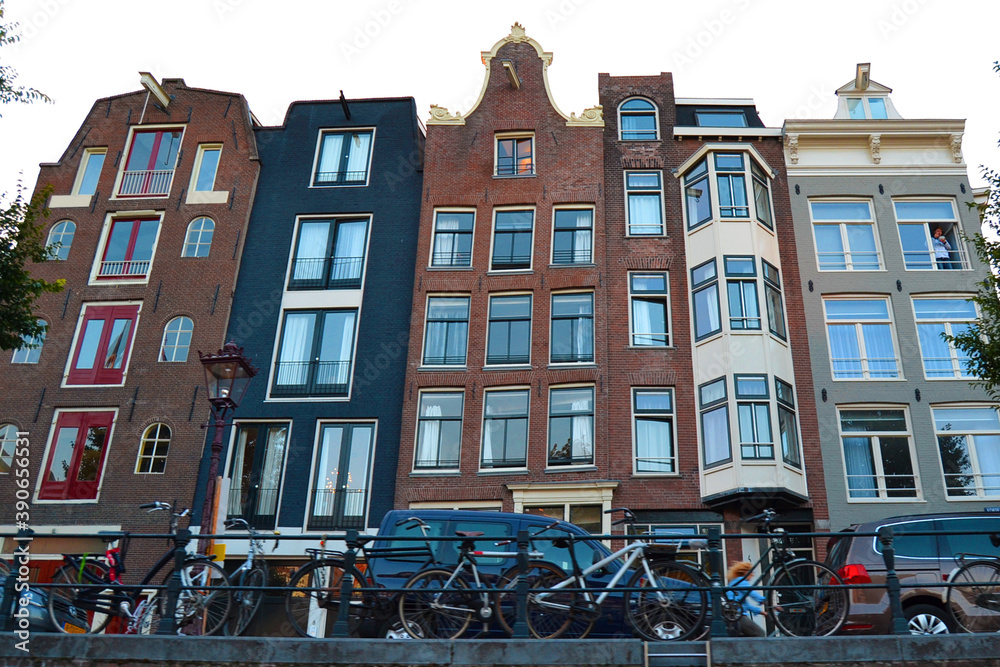 Traditional dutch architecture, facades of houses in Amsterdam, The Netherlands. Bicycle parking in the foreground. Bottom view.