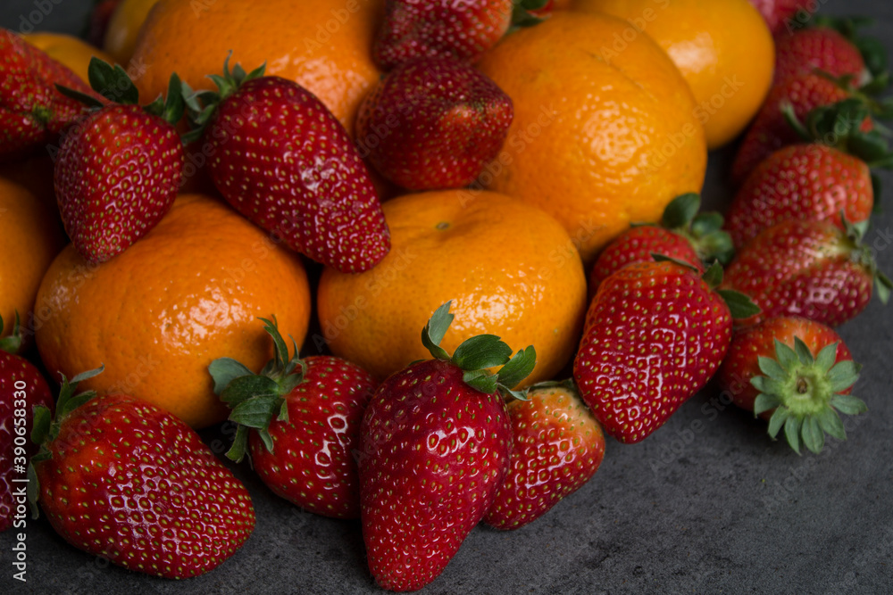 Strawberries and oranges on dark grey background. Fruits top view photo. Fruit diet concept. Strawberries and oranges on dark grey background. Fruits top view photo. Fruit diet concept.