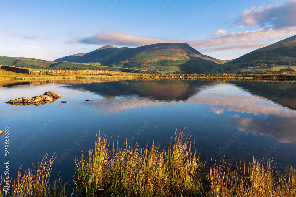 Tewet Tarn and beyond, across the Greta Valley, Lonscale Fell and Skiddaw, reflected in the lake: near Keswick, Lake District National Park, Cumbria, England, UK