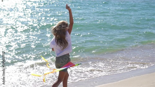 Little girl flying a kite on beach at sunset