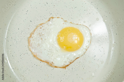 fried chicken egg in a white frying pan top view