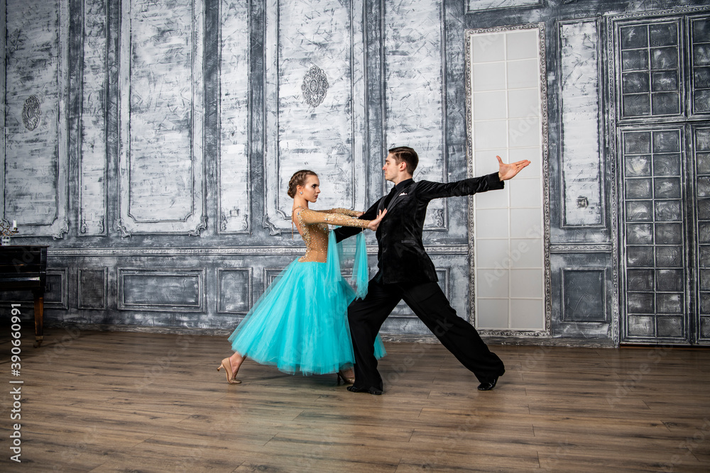 a young man in a black suit is dancing with a girl in a turquoise dress in the dance hall a young man in a black suit is dancing with a girl in a turquoise dress in the dance hall