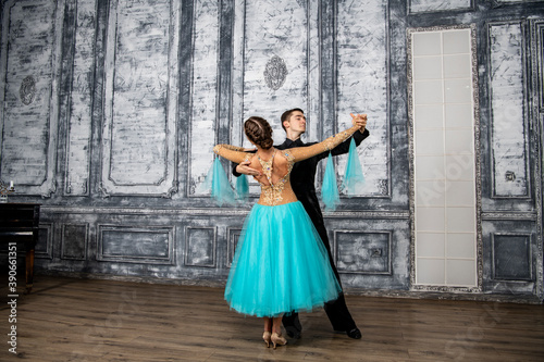 a young man in a black suit is dancing with a girl in a turquoise dress in the dance hall