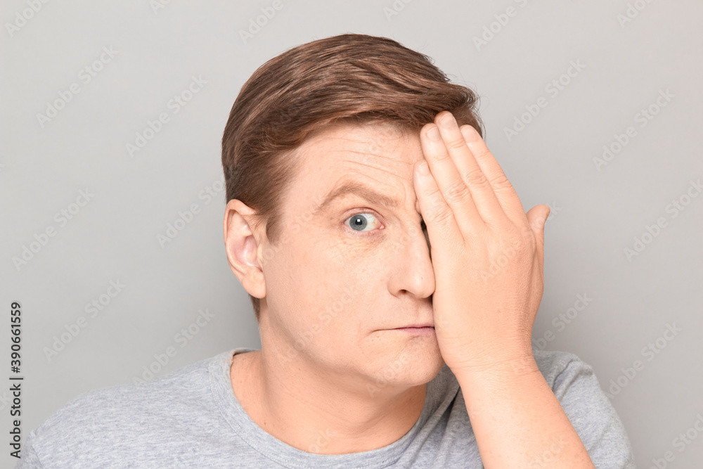 Portrait of mature man looking with one eye at something interesting Portrait of mature man looking with one eye at something interesting