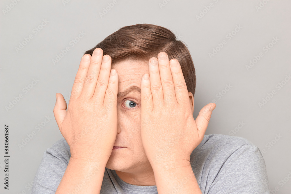 Portrait of curious man looking through gap between hands Portrait of curious man looking through gap between hands