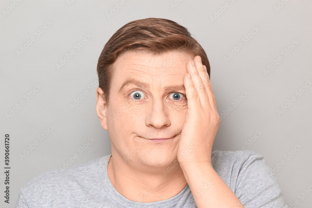 Portrait of confused disappointed man touching his cheek with hand Portrait of confused disappointed man touching his cheek with hand