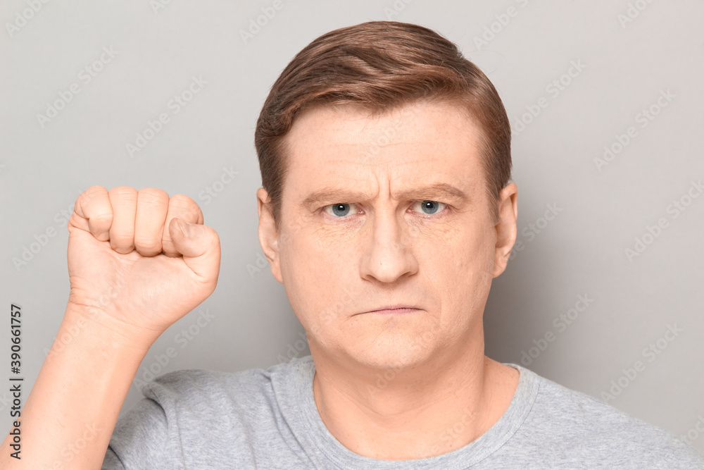Fototapeta premium Portrait of rebellious confident mature man raising fist up