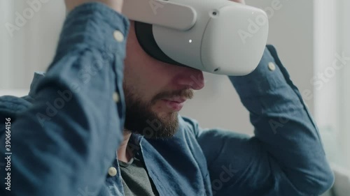 Male Sit on Sofa ant Put On Virtual Reality Glasses