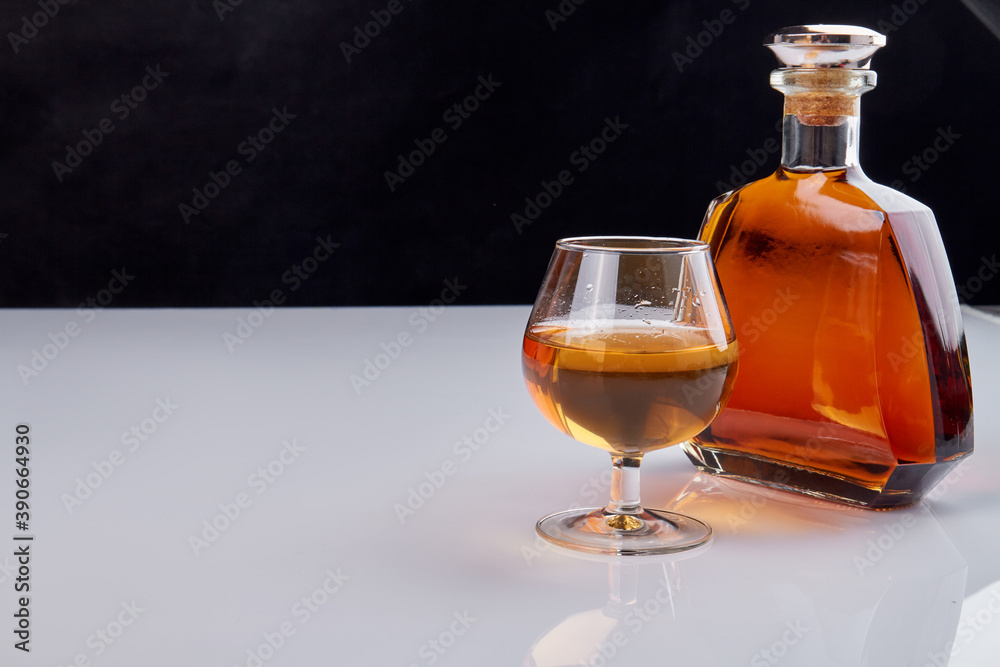 Bottle and glass of whiskey. Bottle with no lables. Black and white background. Bottle and glass of whiskey. Bottle with no lables. Black and white background.