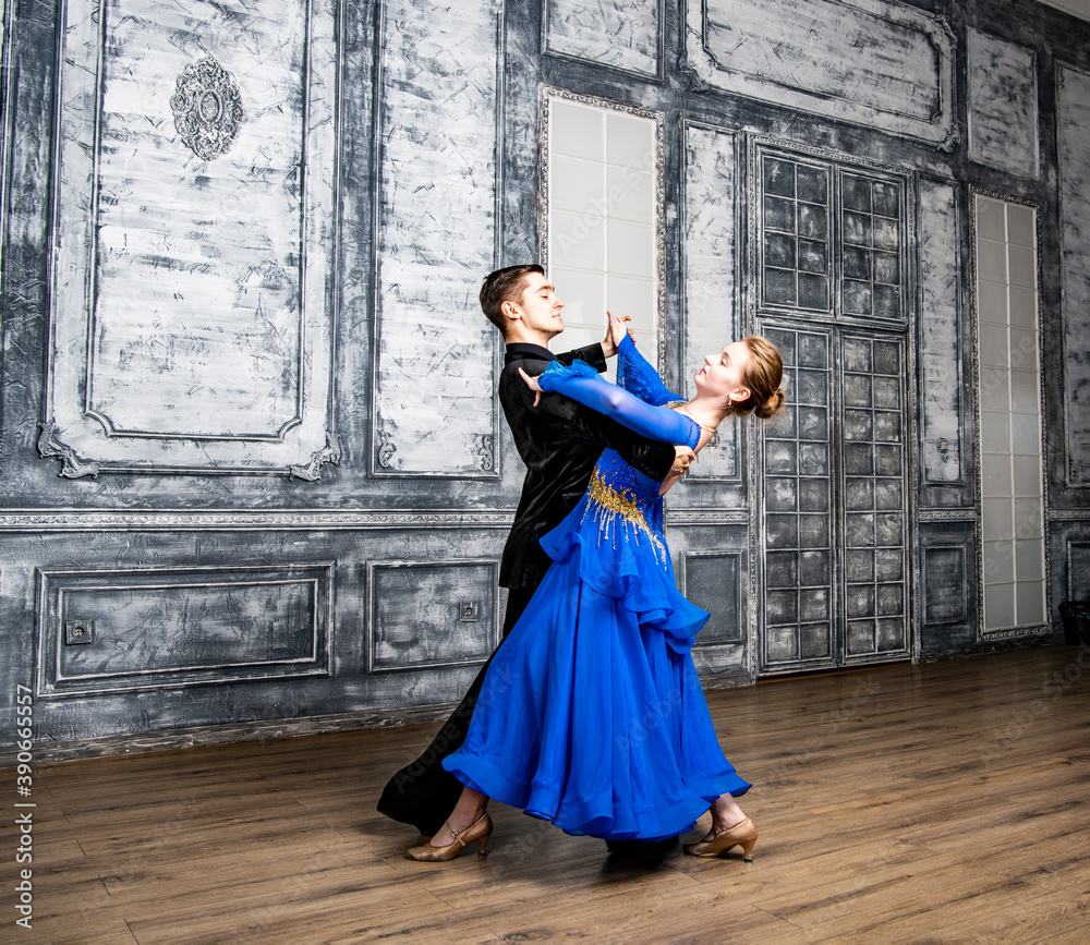 young man dancing with a girl in a blue ballroom dress in a gray dance hall young man dancing with a girl in a blue ballroom dress in a gray dance hall