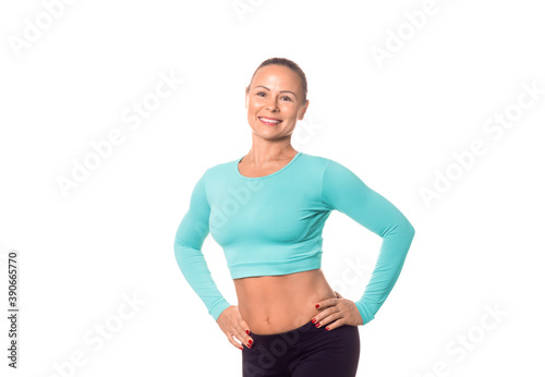 Smiling adult athletic woman in sportswear with good abs and hands on hips  isolated on white. Caucasian model promotes healthy lifestyle  fitness services and products.