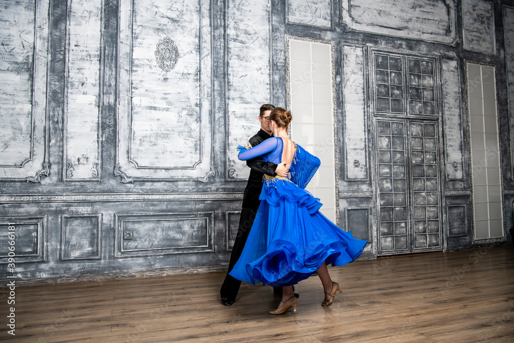 young man dancing with a girl in a blue ballroom dress in a gray dance hall young man dancing with a girl in a blue ballroom dress in a gray dance hall