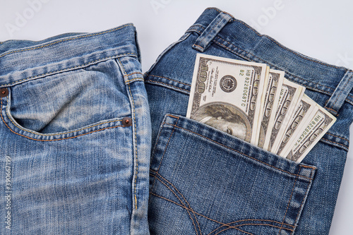 Pairs of jeans with dollars in the pocket. Isolated on white background.