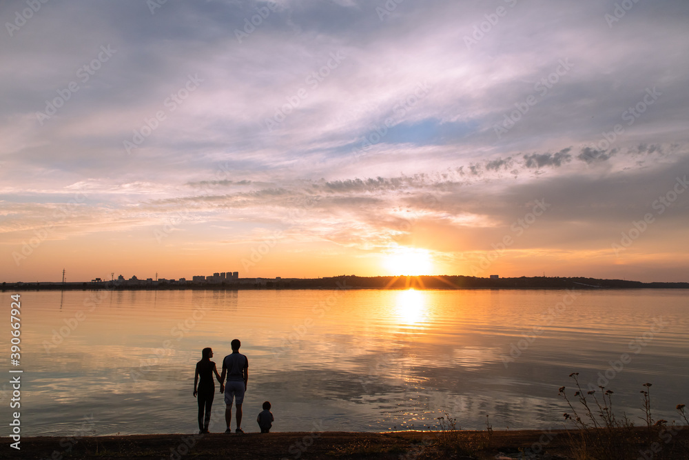 Silhouettes of family on sea beach at sunset