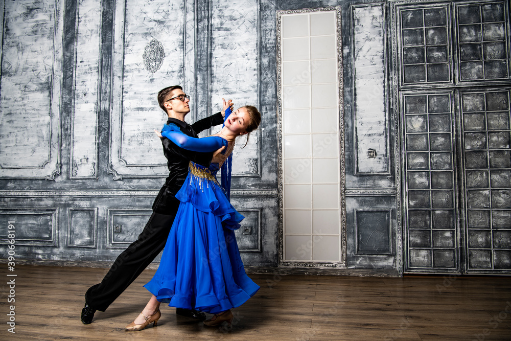 young man dancing with a girl in a blue ballroom dress in a gray dance hall young man dancing with a girl in a blue ballroom dress in a gray dance hall