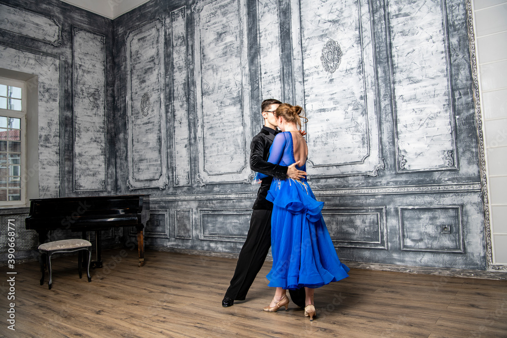 young man dancing with a girl in a blue ballroom dress in a gray dance hall young man dancing with a girl in a blue ballroom dress in a gray dance hall