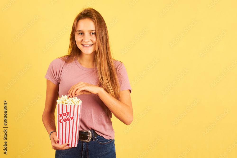 portrait of beautiful woman eating popcorn on a yellow background portrait of beautiful woman eating popcorn on a yellow background