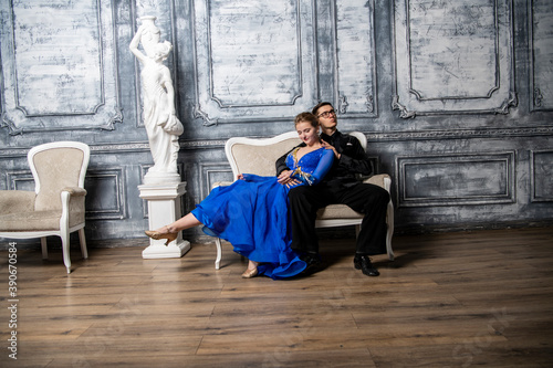 young couple in evening dresses sitting on a white couch in the dance hall