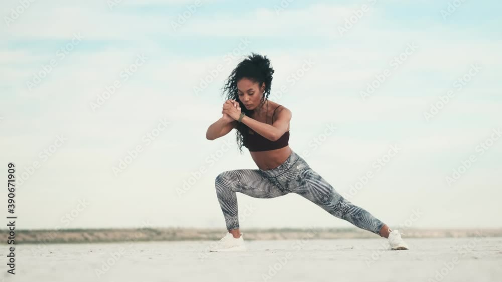 A focused african american woman wearing sportswear is doing exercises outside at the beach A focused african american woman wearing sportswear is doing exercises outside at the beach