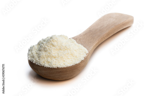 Full fat powdered milk in wooden spoon isolated on white