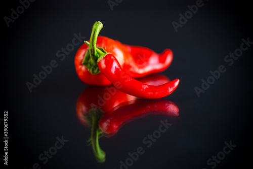 two hot spicy cayenne peppers on black background