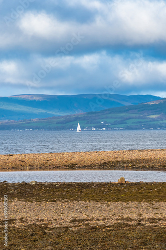 Looking Over to Rothesay and Dunoon from Largs Scotland and a Dramatic Winters Sky.above a White Sailed yacht in the Far distance photo