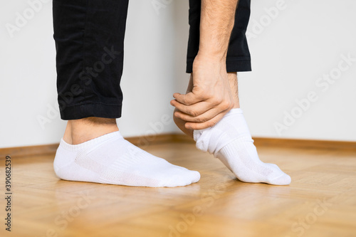 human feet putting on white ankle socks by hand standing on wooden floor photo