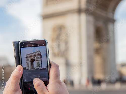 Obraz na płótnie A tourist takes a photo of the Arc de Triomphe with his mobile phone w salonie