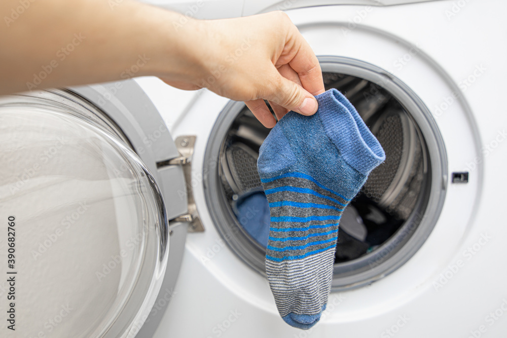 hand in front of front loading washing machine found a blue missing sock hand in front of front loading washing machine found a blue missing sock