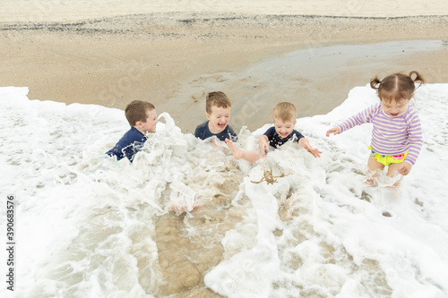 Happy Children Laughing As Waves Crash While Sitting at Edge of Ocean photo